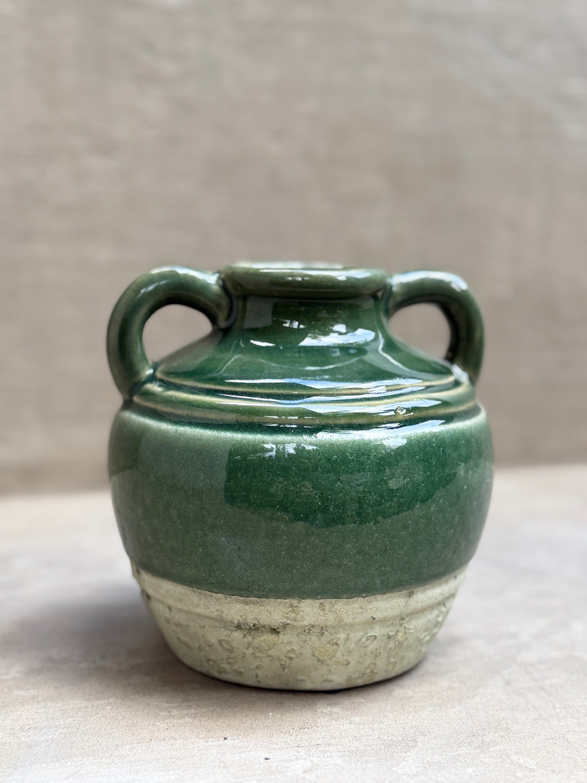 Jarrón de cerámica esmaltada verde con dos asas y base cruda