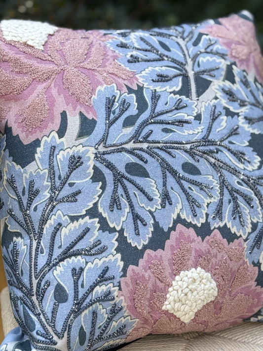 Cojín bordado con flores rosadas y hojas azules